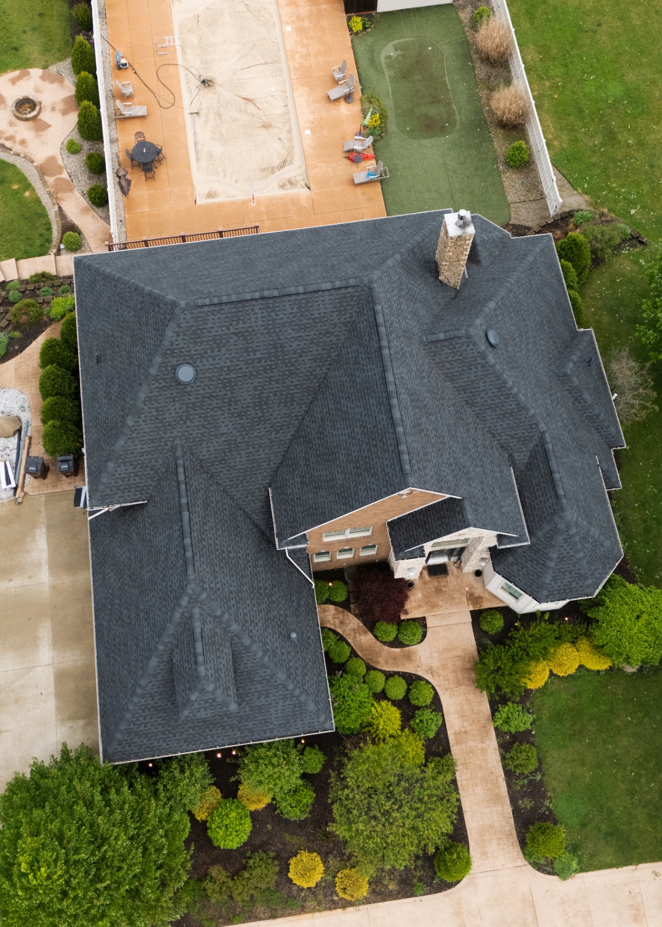 Aerial detail of the completed charcoal GAF Timberline HDZ field with the stone chimney return — Whispering Pines, Bellefontaine, Ohio GAF certified roof replacement by Peak One Restorations