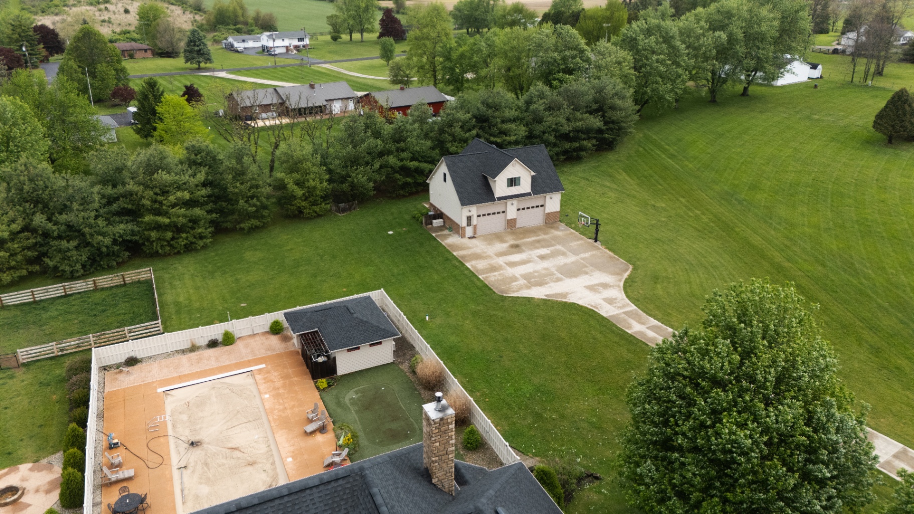 Backyard angle with the new charcoal GAF Timberline HDZ roof and stone chimney visible at the foreground — Whispering Pines, Bellefontaine, Ohio
